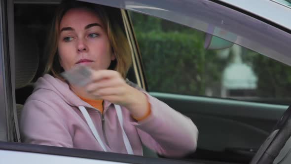 Portrait of sad young woman is driving a car and gives her license to a policeman.