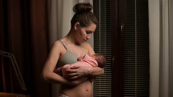 Breastfeeding a newborn baby, a woman holds her son in her arms and feeds him