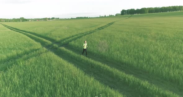 Sporty Child Runs Through a Green Wheat Field