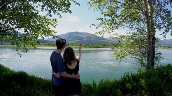 Couple standing with arm around watching the lake 4k