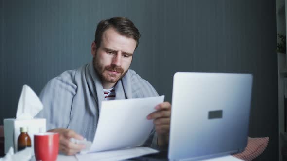 Young Freelancer Working From Home During Illness. Sick Business Man Working with Laptop Computer