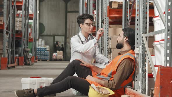 Doctor Examining Warehouse Worker in Workplace