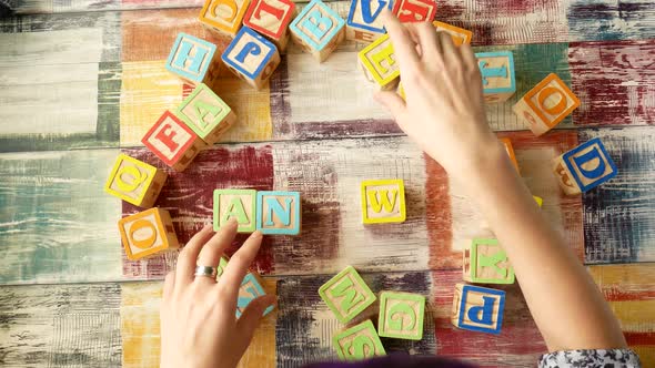Top View of the Desktop. Women's Hands Add the Word "ANSWER" From Wooden Cubes