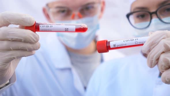 Two Doctors Exploring Test Tubes with Blood Samples To Coronavirus. Male and Female Medics with