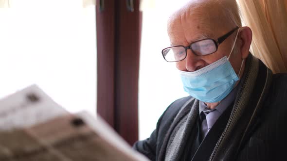 Old Grandfather Reads the Press While Sitting in a Cafe