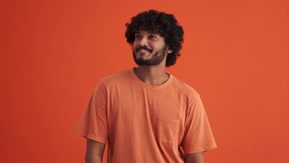 Smiling curly-haired Indian man hoping for something