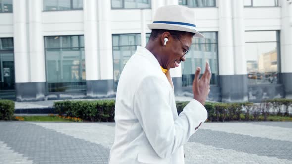 Joyful black man in wireless headphones listens to music