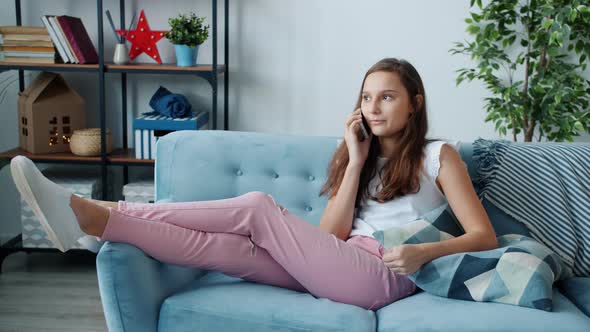 Emotional Teenager Enjoying Conversation on Mobile Phone Relaxing on Couch in Living Room