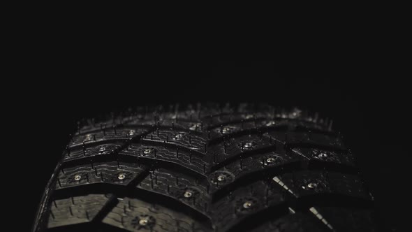 Car Winter Tire with Studded on Black Background