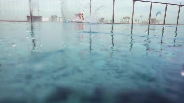 Active Young Woman Diving in Pool and Splashing Water