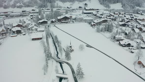 High aerial orbit of small snow covered church