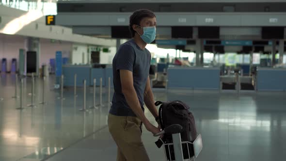 Man in Mask at Empty Airport at Check in in Coronavirus Quarantine Isolation Returning Home Flight