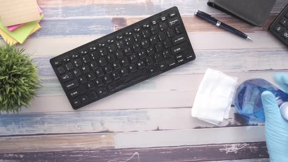 Hand in Blue Rubber Gloves and White Tissue Disinfecting Keyboard