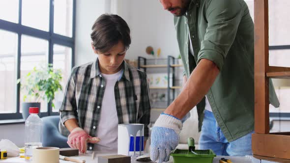 Father and Son Stirring Grey Color Paint at Home