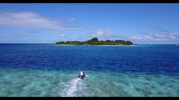 Aerial flying over panorama of tranquil lagoon beach holiday by blue sea with clean sandy background