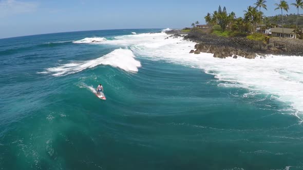 Aerial view of a man sup stand-up paddleboard surfing in Hawaii