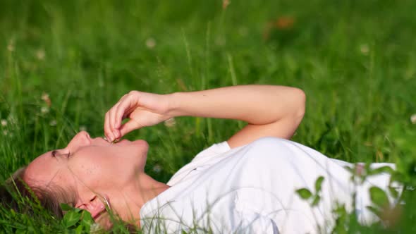 Blonde Girl Relaxes Lying on the Green Grass