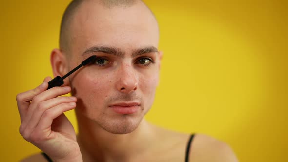 Male Caucasian Extravagant Transsexual Man Applying Mascara on Eyelashes