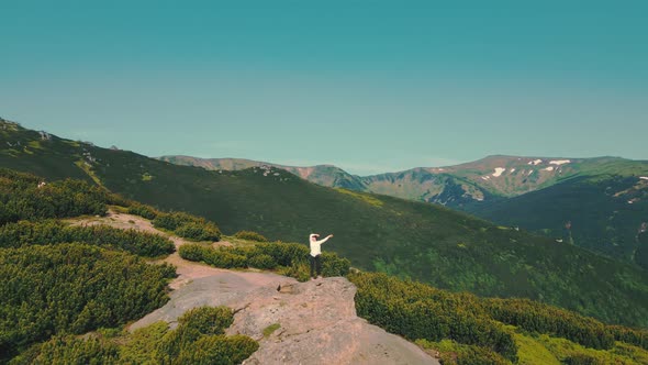 Woman Standing on a Rock with Arms Raised From Aerial View