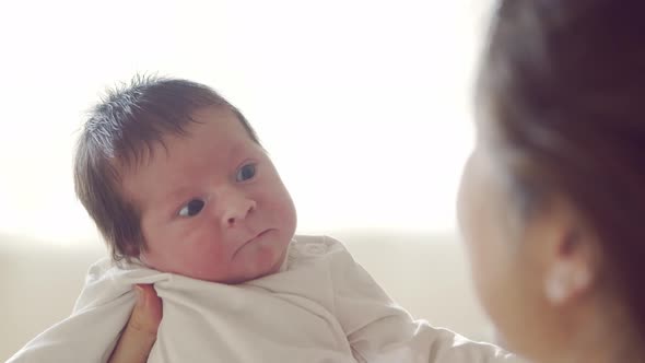 Newborn baby boy and his mother at home. Close-up portrait of the infant