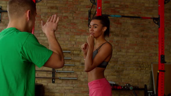 Athletic Woman Boxer Throwing Jab During Training Session with Male Trainer