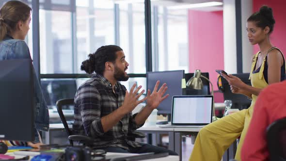 Diverse group of work colleagues sitting at desk and discussing