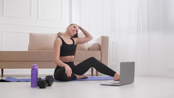 Young Brunette Warming Up While Watching Fitness Video Online at Home