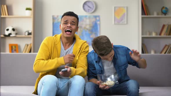 African-American and Caucasian Friends Watching Comedy Show on TV Eating Popcorn