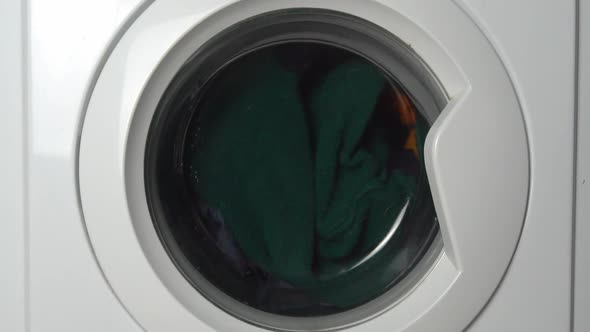 Close-up of a washing machine washing colored clothes.