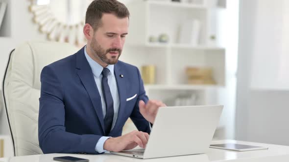 Sick Businessman with Laptop Coughing in Office