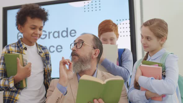 Pupils Discussing Funny Book with Old Teacher