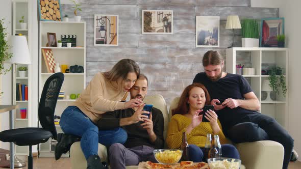 Group of Friends Sitting on Couch Using Their Smartphones