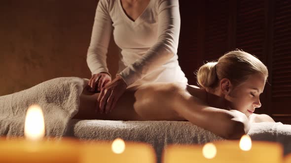 Young, healthy and beautiful woman gets massage therapy in the spa salon.