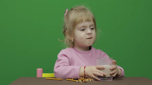 The Child Eats Cookies. A Little Girl Is Eating Cookies Sitting on the Table.