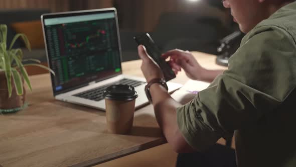 Asian Man Trader Investor Sitting In A Wheelchair Using Phone And Laptop Trading Cryptocurrency