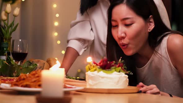 Happy little girl celebrating her birthday with Lgbt family blowing out the candles