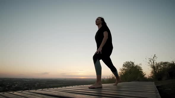 Woman Stand on Yoga Mat and Practicing Yoga Stretching Exercise Outdoors in Sunset