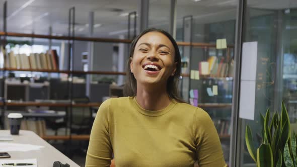 Portrait of happy biracial businesswoman in empty office