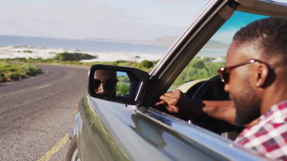 African american man adjusting side rear view mirror while sitting in convertible car