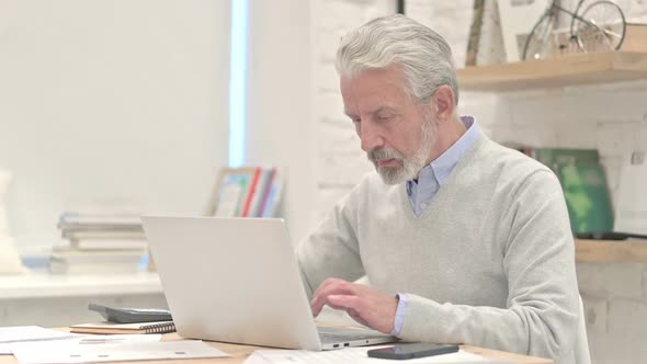 Old Man Typing on Laptop at Work