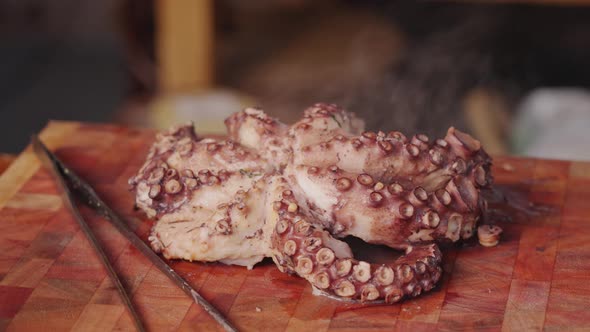 Cinematic food videography tracking shot of freshly cooked octopus placed on a chopping board with s