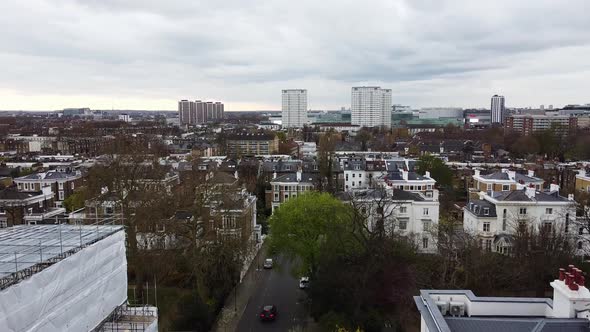 Ascending aerial shot over residential area in London and high rising blocks in background. Notting