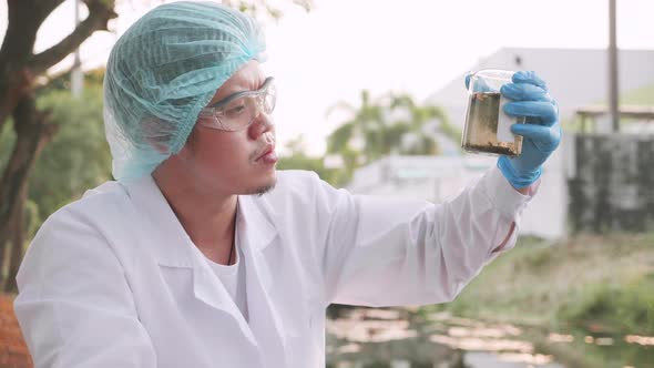 Scientist takes samples of factory wastewater a test tube for analysis in lab.