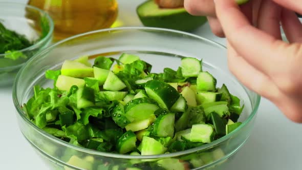 Woman Cooking Salad of Fresh Green Vegetables and Herbs