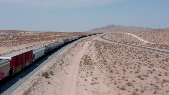 A freight train moves across the desert from a high angle.