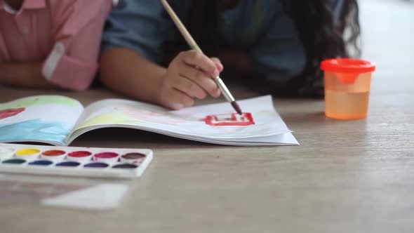 A Little Boy and a Little Girl Paint with Paint on the Album Lying on the Floor