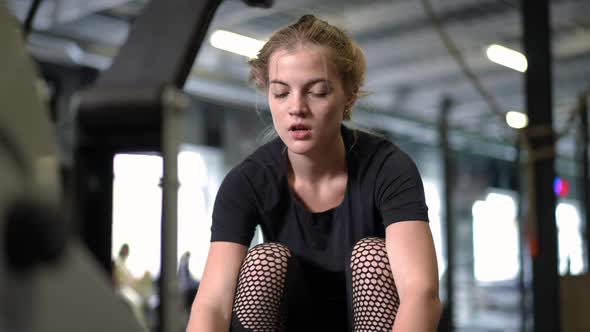 Portrait of Tired Young Beautiful Sportswoman Ending Exercise on Gym Pull Machine Sighing