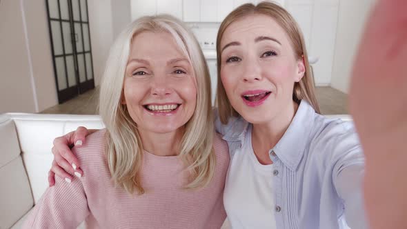 Happy Affectionate Mature Mother and Grownup Daughter Make Selfie Video Call By Mobile Phone While