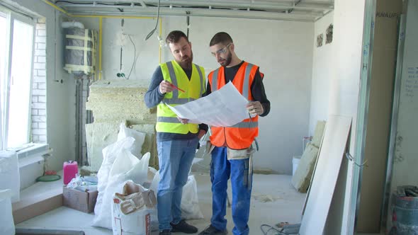 Male Builders Discussing Draft During Renovation Works