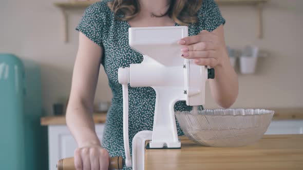 Girl Mills Wheat Grains with Home Grinder at Wooden Table